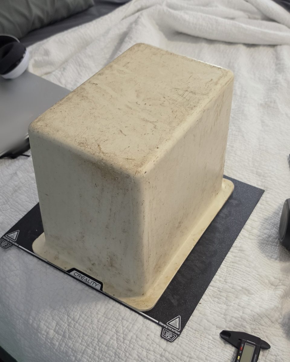 Original factory storage box from a vintage center console, yellowed and stained after decades in the sun, sitting upside down on a 3D printer bed
